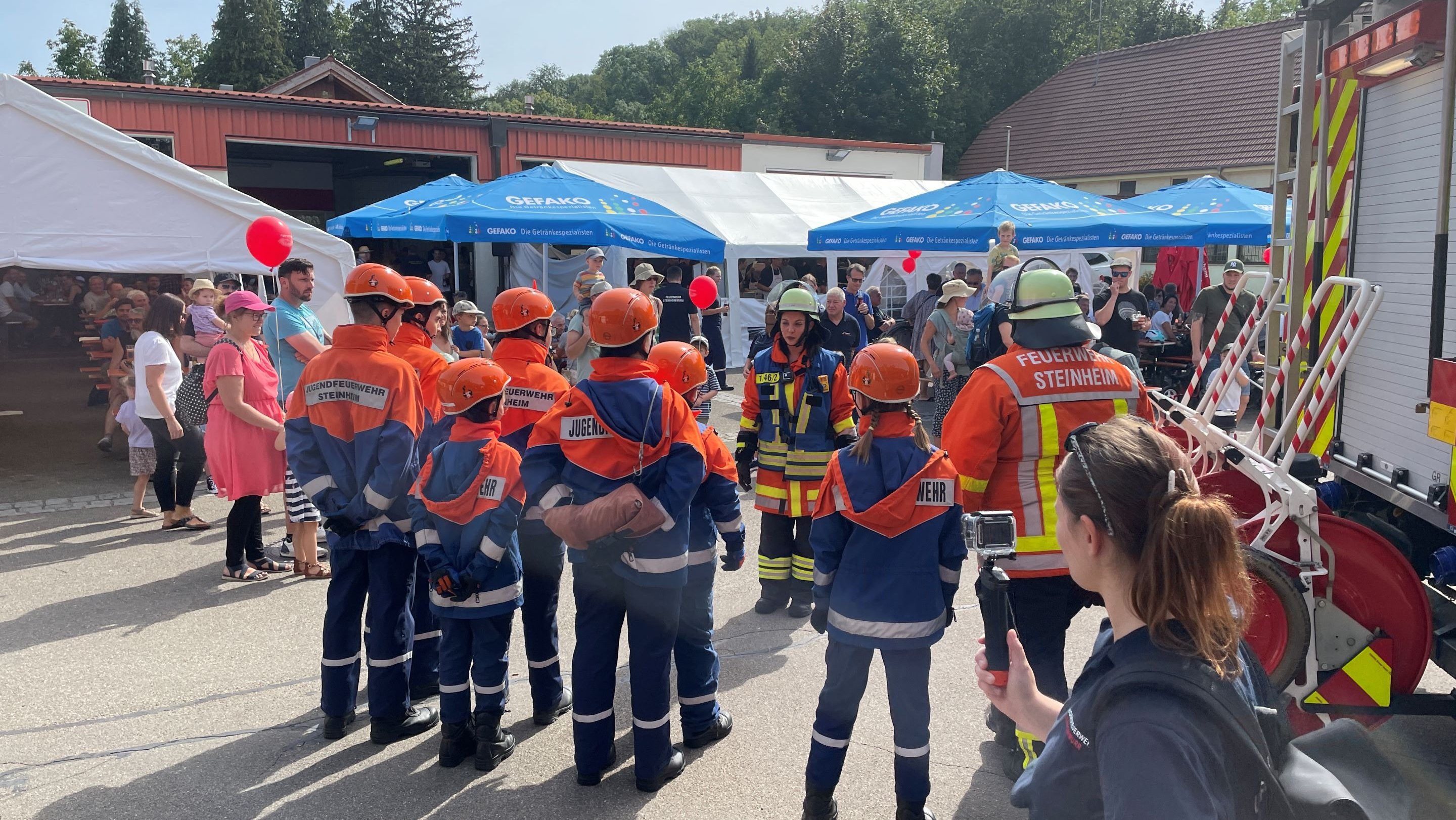 Die Mitglieder der Jugendfeuerwehr stehen hinter einem Feuerwehrfahrzeug