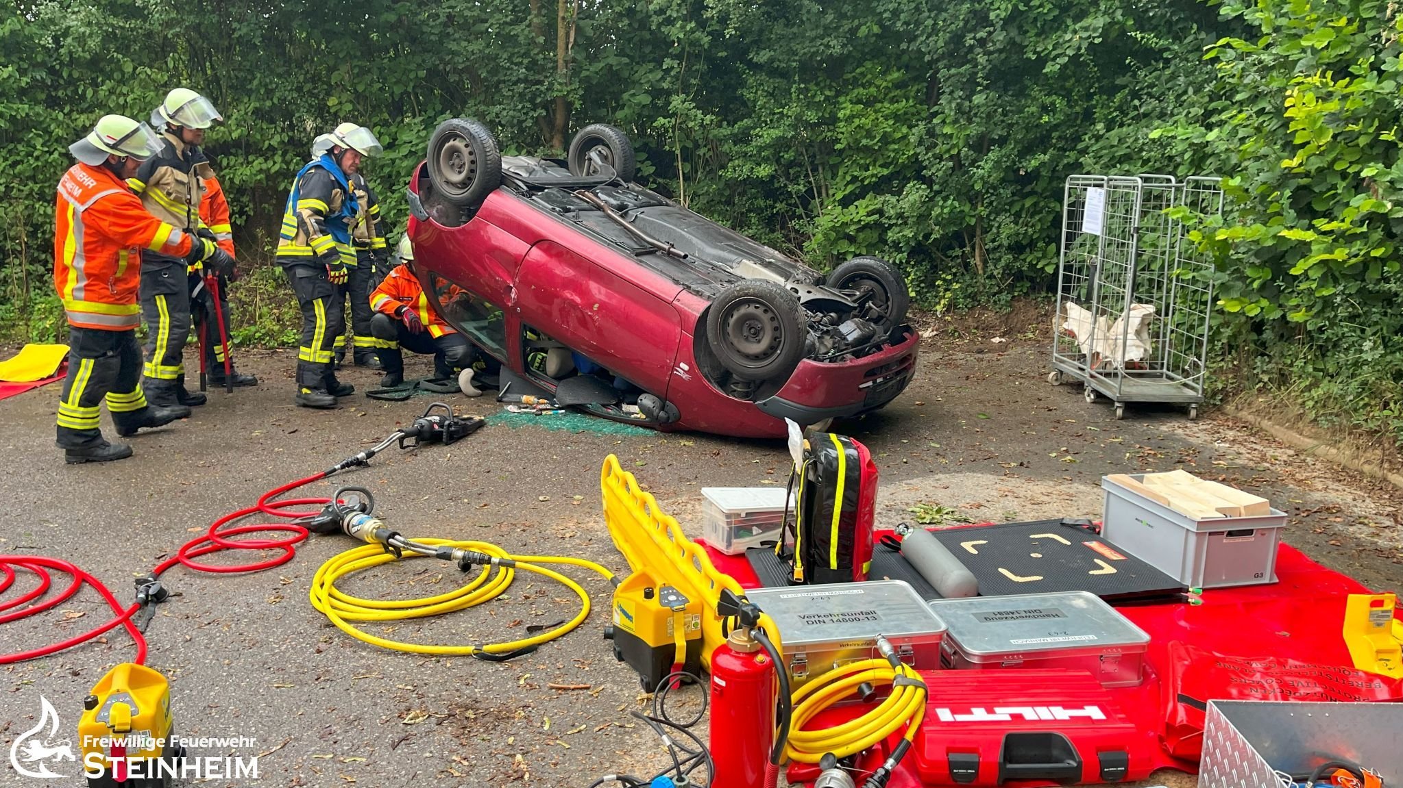 Mehrere Feuerwehrmänner arbeiten am Unfallfahrzeug