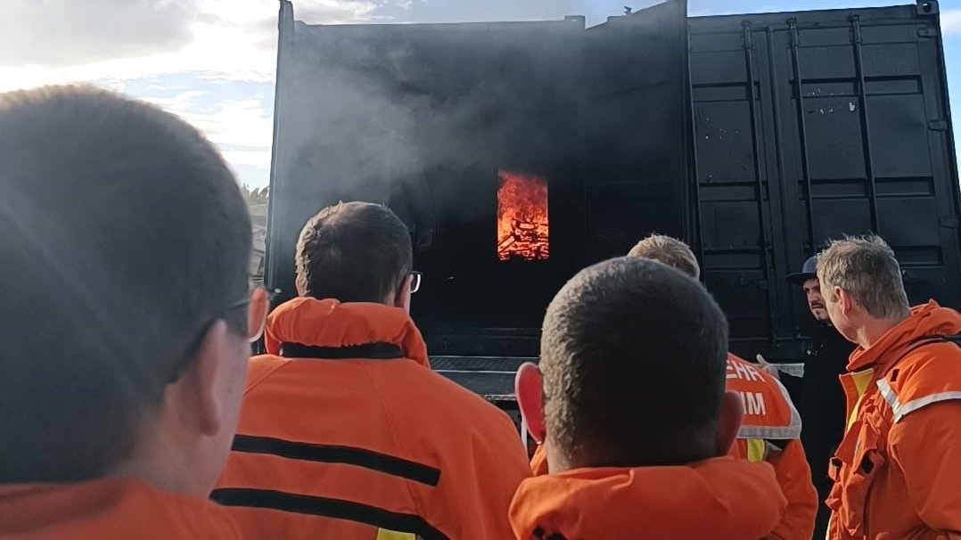 Einsatzkräfte beobachten Feuer vor dem Brandcontainer