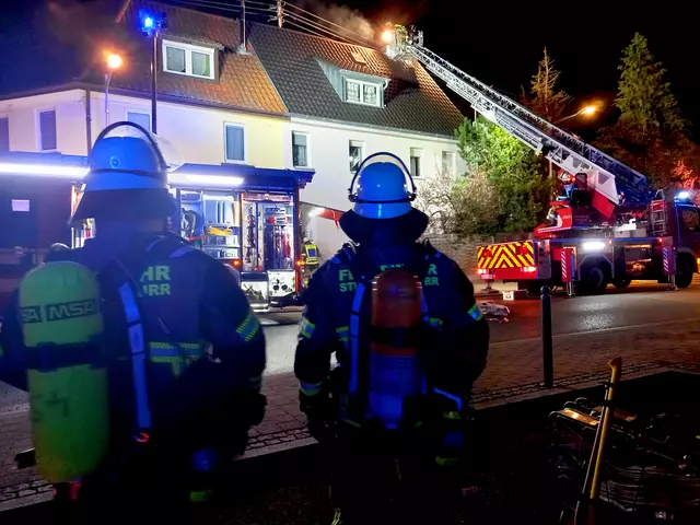 Feuerwehrleute und die Drehleiter stehen vor dem Brandobjekt