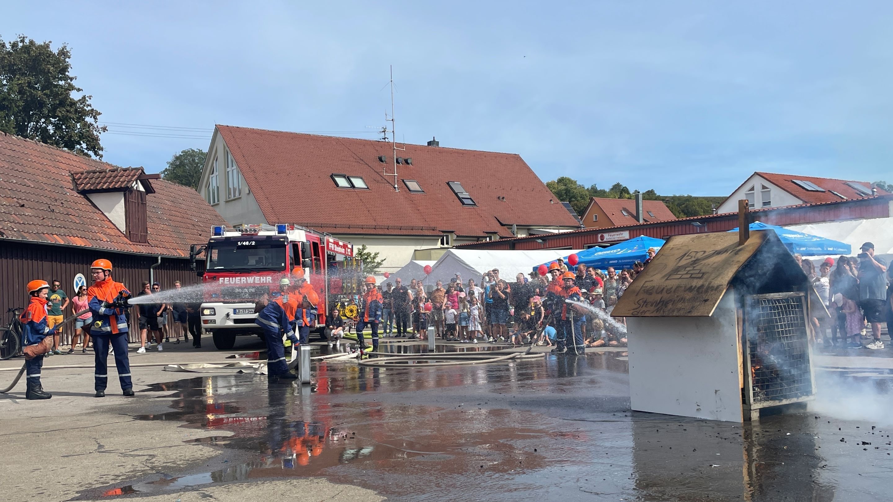 Mitglieder der Jugendfeuerwehr löschen ein brennendes Holzhäuschen