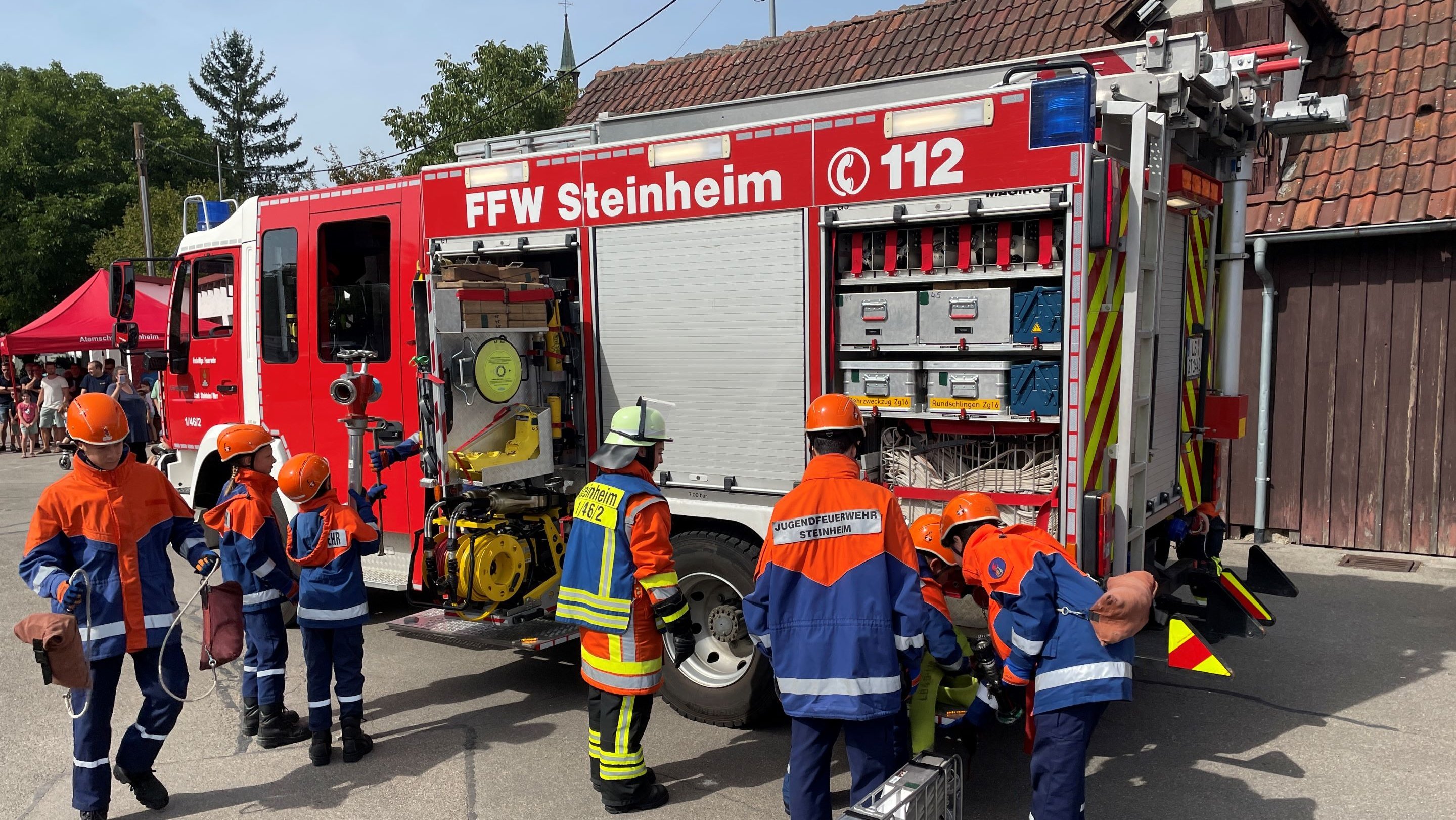 Mitglieder der Jugendfeuerwehr entnehmen Gegenstände aus einem Feuerwehrfahrzeug