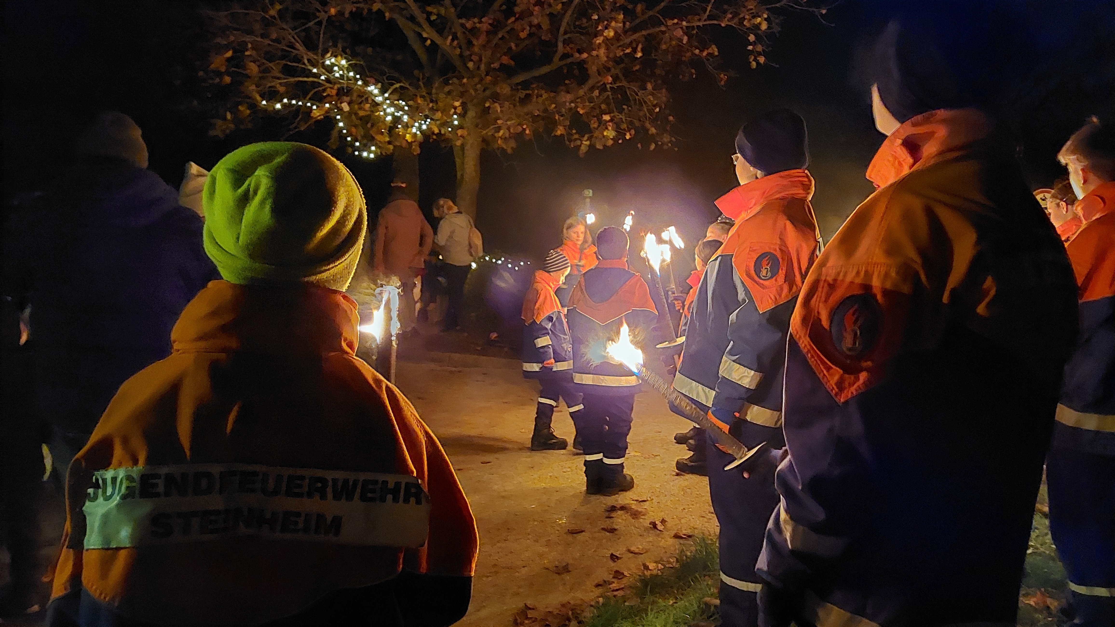 Mitglieder der Jugendfeuerwehr in Uniform halten Fackeln